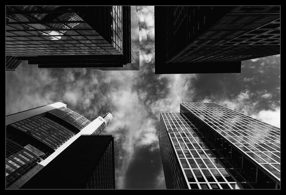 Blick von unten nach oben in einer von Wolkenkratzern umgebenen Kreuzung.In jeder Ecke steht einer.